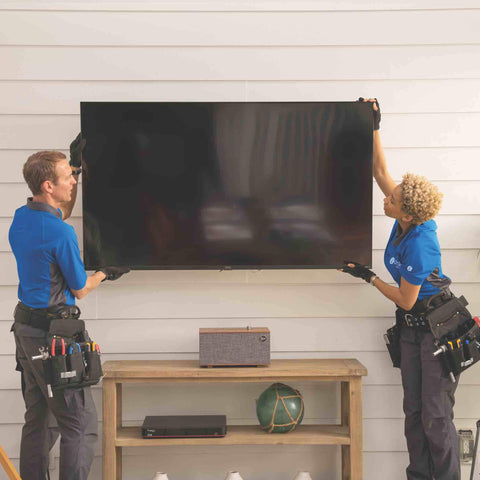 2 technicians installing and mounting a large TV outdoors